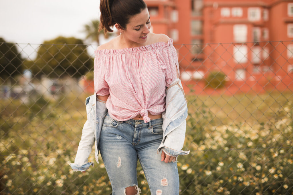 fashionable young woman standing front fence looking away